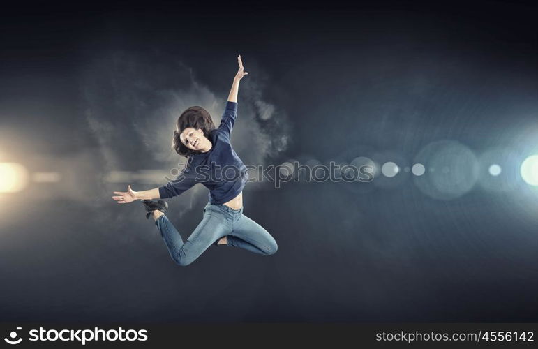 Dancer girl in jump. Young woman dancer jumping in spotlights on dark background