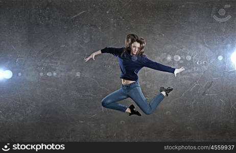 Dancer girl in jump. Young woman dancer jumping in spotlights on dark background