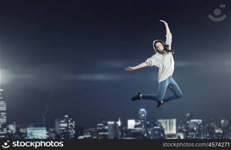 Dancer girl in jump. Young woman dancer jumping in spotlights on dark background