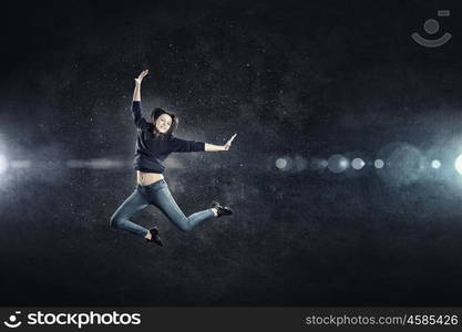 Dancer girl in jump. Young woman dancer jumping in spotlights on dark background