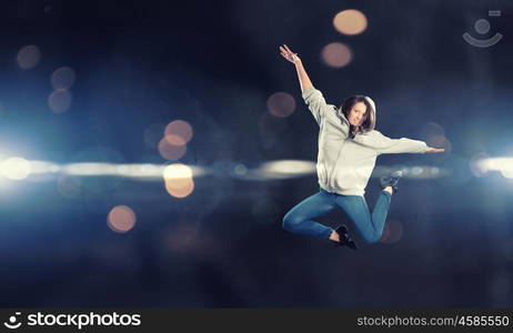 Dancer girl in jump. Young woman dancer jumping in spotlights on dark background