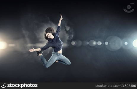 Dancer girl in jump. Young woman dancer jumping in spotlights on dark background