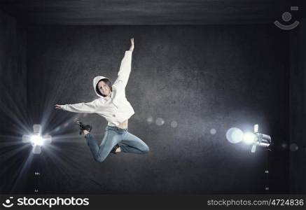 Dancer girl in jump. Young woman dancer jumping in spotlights on dark background
