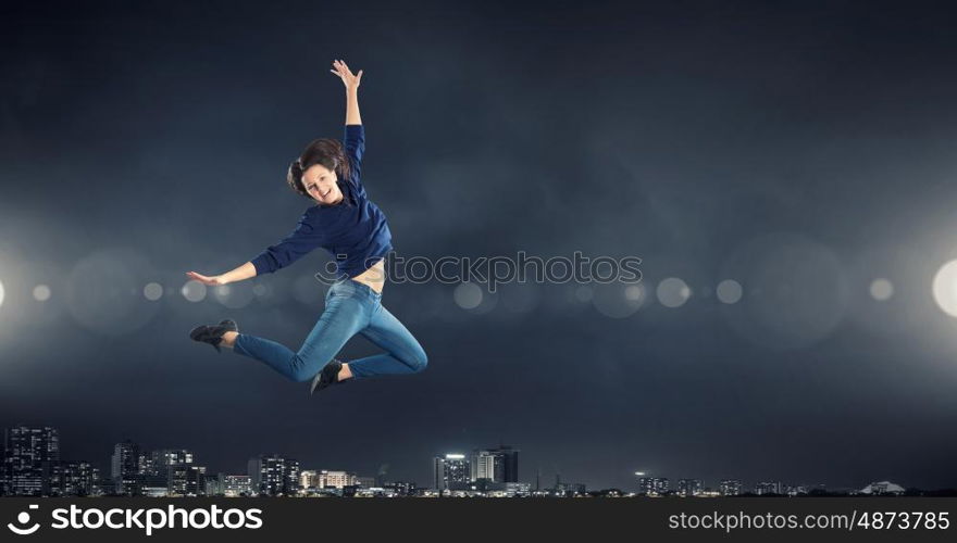 Dancer girl in jump. Young woman dancer jumping in spotlights on dark background