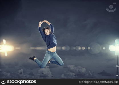 Dancer girl in jump. Young woman dancer jumping in spotlights on dark background