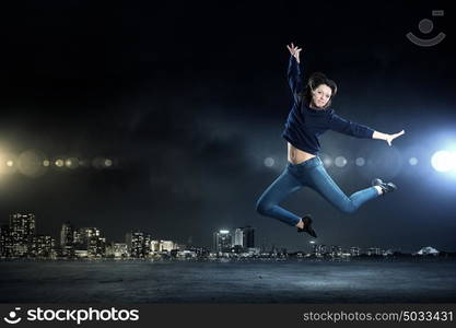 Dancer girl in jump. Young woman dancer jumping in spotlights on dark background