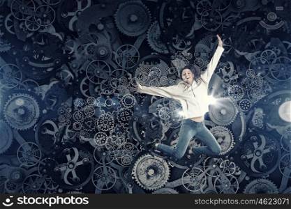 Dancer girl in jump. Young woman dancer jumping in spotlights on gears background
