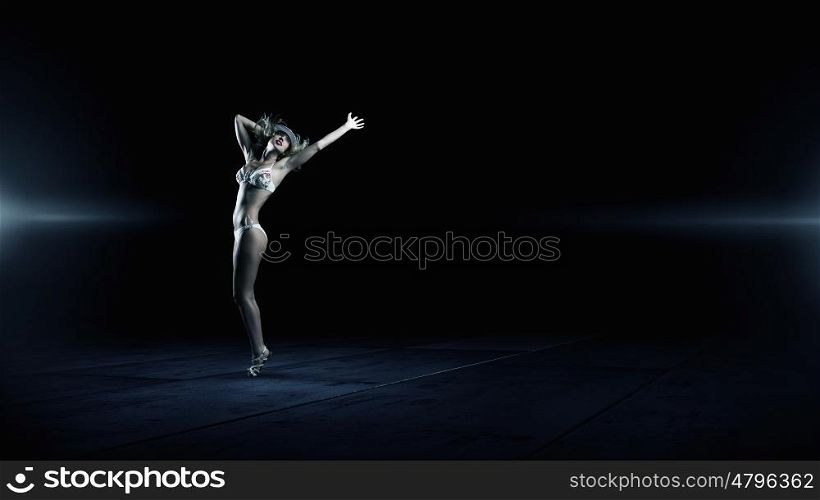 Dancing blonde in bikini. Hot young dancing woman in white bikini on dark background