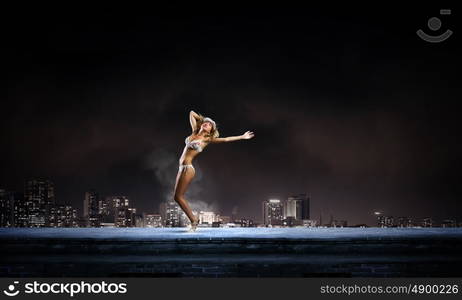 Dancing blonde in bikini. Hot young dancing woman in white bikini on dark background