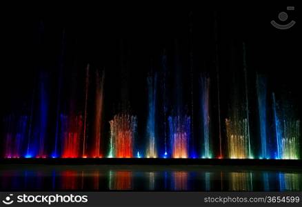 Dancing colorful fountain with reflection on ice.