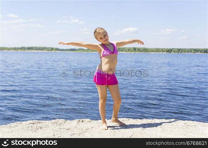 Dancing girl on the riverbank in pink swimsuit