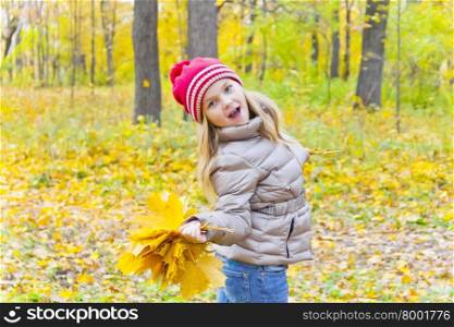 Dancing girl with bouquet from sheets in autumn