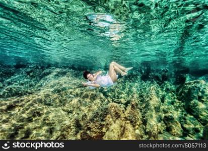 Dancing underwater, beautiful young female swimming in the sea near beautiful coral garden, active lifestyle, summer holidays and vacation concept