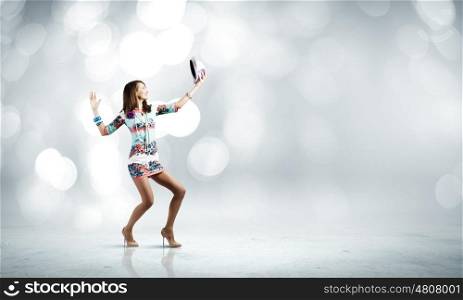 Dancing woman. Young woman in colored dress and hat dancing against bokeh background