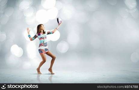 Dancing woman. Young woman in colored dress and hat dancing against bokeh background