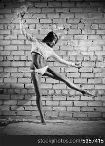 Dancing young woman on grey wall (monochrome version)