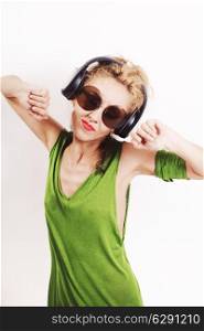 Dancing young woman wearing headphones and sunglasses on a white background