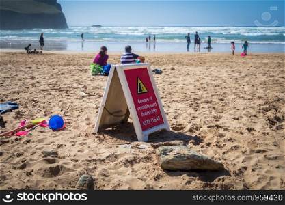 Danger sign warning beach users of potential unstable sand dunes and cliffs in Cornwall, UK