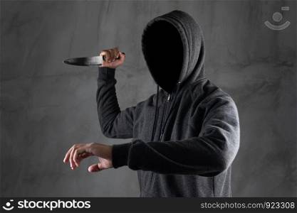 Dangerous hooded man standing in the dark and holding a knife Face can not be seen.