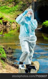 dangerous sewer water, a scientist takes a sample of water in protective clothing
