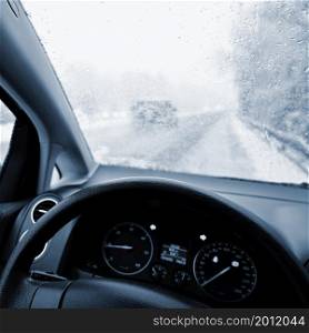 Dangerous winter season with snow on the road. The interior of the car from the driver&rsquo;s point of view - dangerous traffic in bad weather.