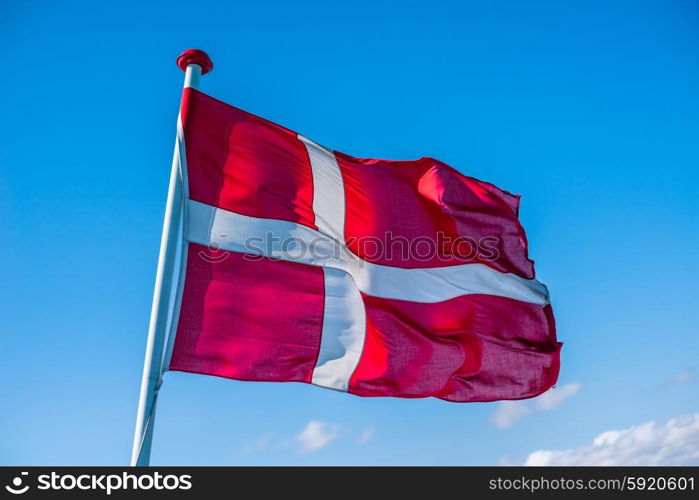 Danish flag in the wind on blue background