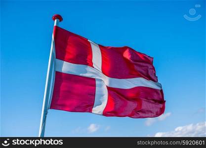 Danish flag in the wind on blue background