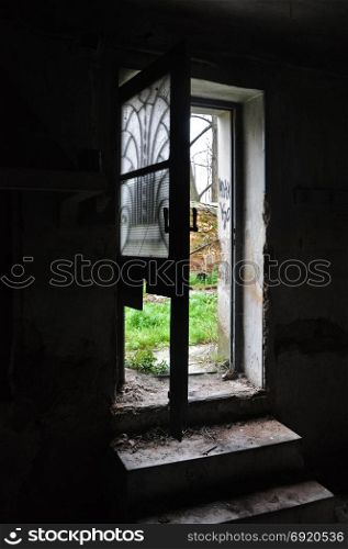 Dark abandoned house interior dirty steps and light through broken door with antique metalwork motif.