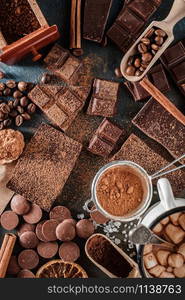 Dark and milk chocolate bars with dry orange slices, cinnamon sticks and coffee beans on blue background