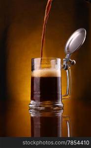 Dark beer pouring into a mug from above over a dark background