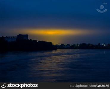 Dark blue sky with yellow city lights. View from the river. Night sky with reflection of the yellow lights of the city