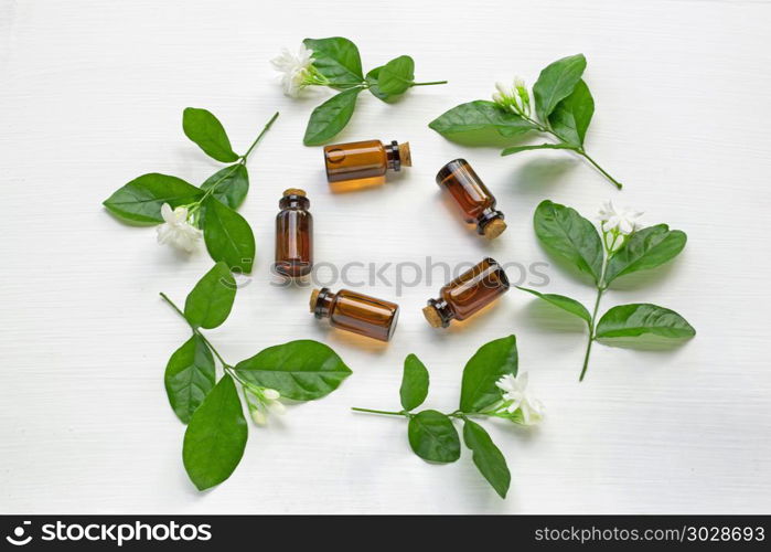 Dark brown Bottles of essential oil with jasmine flower.. Dark brown Bottles of essential oil with jasmine flower and leaves on white background.