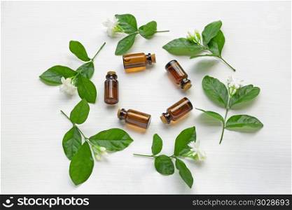 Dark brown Bottles of essential oil with jasmine flower.. Dark brown Bottles of essential oil with jasmine flower and leaves on white background.