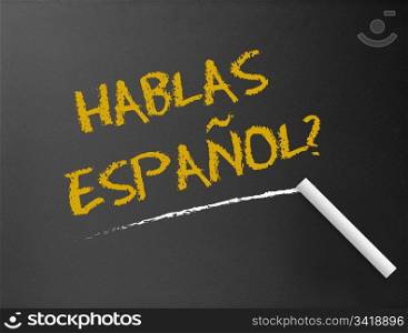 Dark chalkboard with a question. Hablas Espanol?