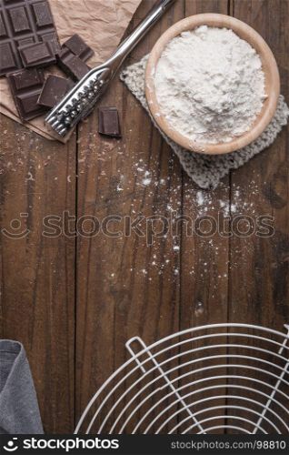 Dark chocolate and flour on rustic background and space for text.