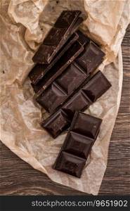 Dark Chocolate bars on crumbled paper and brown wooden background