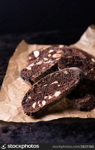 Dark chocolate biscotti with nuts on baking paper, selective focus