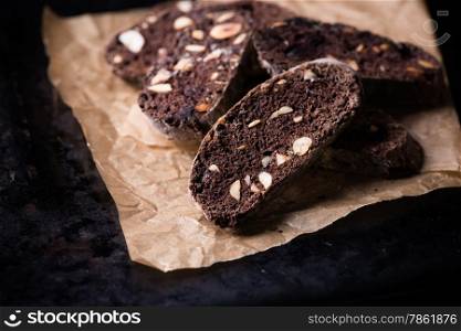 Dark chocolate biscotti with nuts on baking paper, selective focus