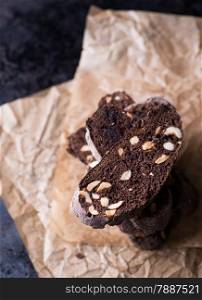 Dark chocolate biscotti with nuts on baking paper, top view, selective focus