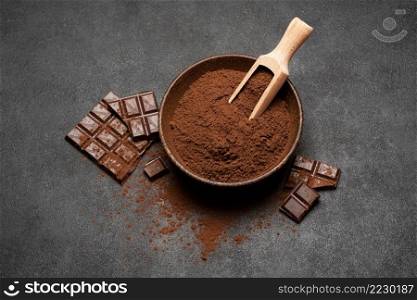 Dark Chocolate chunks and cocoa powder in wooden bowl on dark concrete background or table. Dark Chocolate chunks and cocoa powder in wooden bowl on dark concrete background