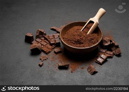 Dark Chocolate chunks and cocoa powder in wooden scoop on dark concrete background or table. Dark Chocolate chunks and cocoa powder in wooden scoop on dark concrete background