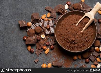 Dark Chocolate chunks, nuts and cocoa powder in wooden bowl on dark concrete background or table. Dark Chocolate chunks, nuts and cocoa powder in wooden bowl on dark concrete background