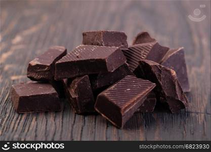 dark chocolate. Pieces of natural dark chocolate on wooden table