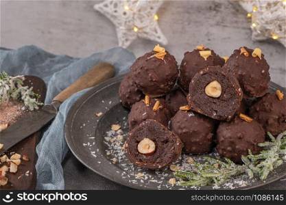 Dark chocolate truffles with hazelnuts on plate.