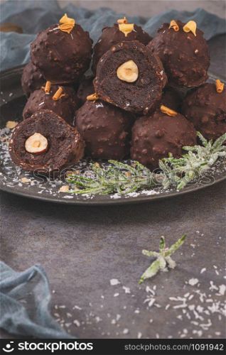 Dark chocolate truffles with hazelnuts on plate.