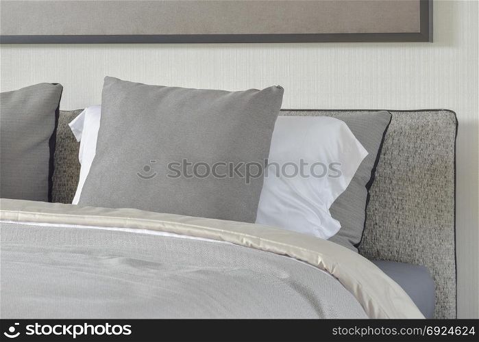 Dark gray and white pillows setting on bed with comfy blanket