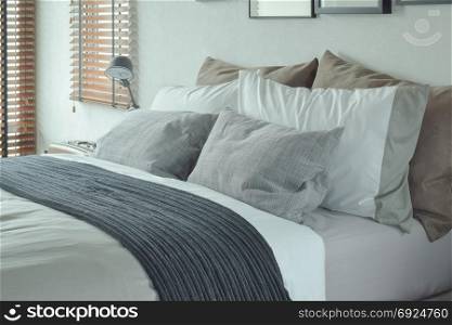 Dark gray bed runner with gray and brown pillows on bed