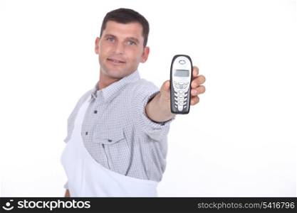 Dark haired man holding out mobile telephone