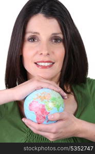 dark-haired smiling woman holding globe in both hands