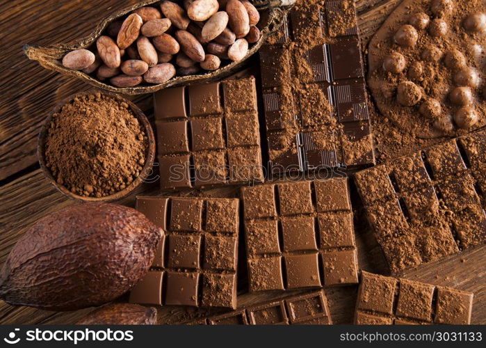 Dark homemade chocolate bars and cocoa pod on wooden . Milk and dark chocolate on a wooden table